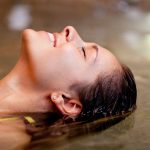 Donna sorridente che si rilassa in una vasca grazie ai benefici dell’acqua termale salsobromoiodica