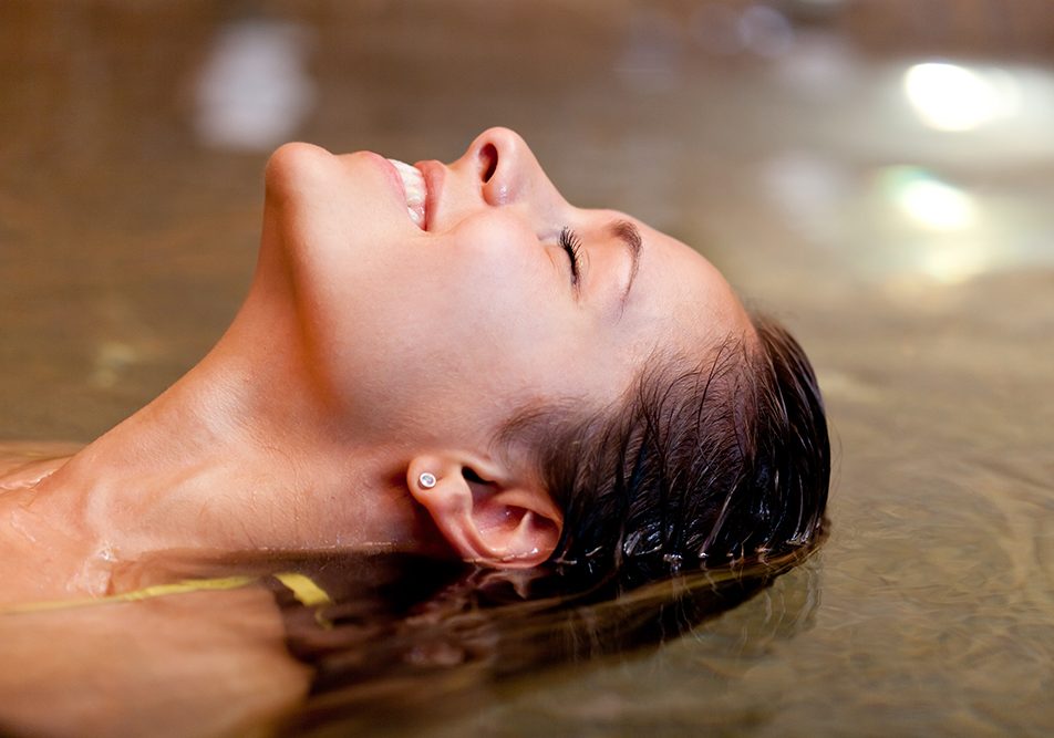 Donna sorridente che si rilassa in una vasca grazie ai benefici dell’acqua termale salsobromoiodica