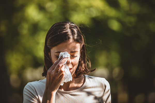 Donna che utilizza un fazzoletto per gli occhi gonfi e lacrimanti a causa di un’allergia primaverile