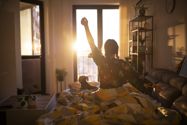 Giovane donna appena sveglia che si espone alla luce solare del mattino per regolare il ritmo circadiano