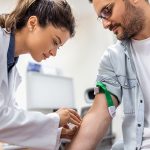 In una sala ospedaliera, la dottoressa prepara il paziente all’esame del sangue per verificare l’eventuale presenza dei trigliceridi alti