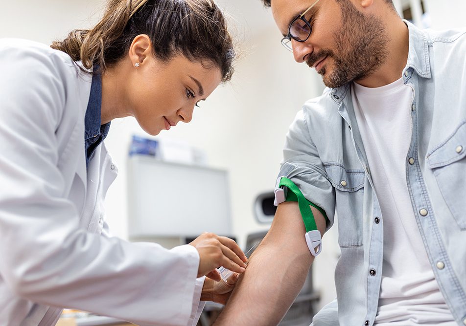 In una sala ospedaliera, la dottoressa prepara il paziente all’esame del sangue per verificare l’eventuale presenza dei trigliceridi alti