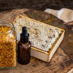 Miele biologico e boccetta contenete polline e propoli, antibiotico naturale, su pala di legno
