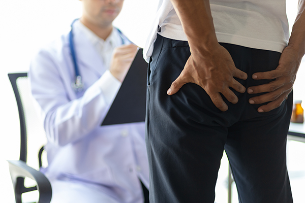 Paziente che, durante la visita medica, lamenta dolore nella zona sacro-coccigea e riceve informazioni sull’intervento mini-invasivo per rimuovere la cisti pilonidale