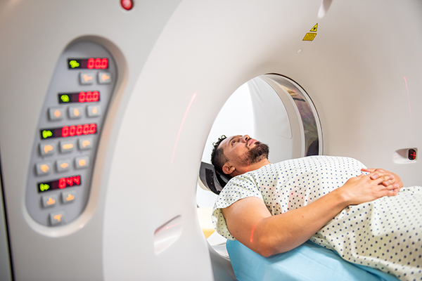 Paziente presso un centro diagnostico, sdraiato su un lettino, che si sottopone a una tomografia computerizzata (TC) per diagnosticare la neoplasia cerebrale