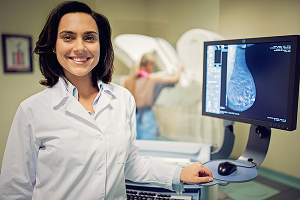 Medico radiologo in cabina che svolge una mammografia su una paziente femminile con sospetta neoplasia della mammella