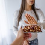 Ragazza con allergia alimentare alle arachidi che rifiuta l’offerta di tale snack, servito su un vassoio nella versione tostata e salata