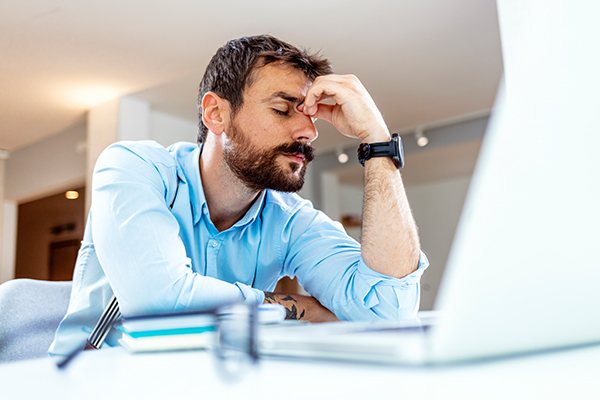 Uomo a lavoro davanti al computer, in seguito ad un sonno poco ristoratore, mentre si interroga sulle cause dello svegliarsi sempre stanco