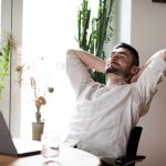 Uomo seduto al tavolo di casa davanti al laptop, che avverte dolore al collo e si domanda se la Tachipirina va bene per il dolore cervicale