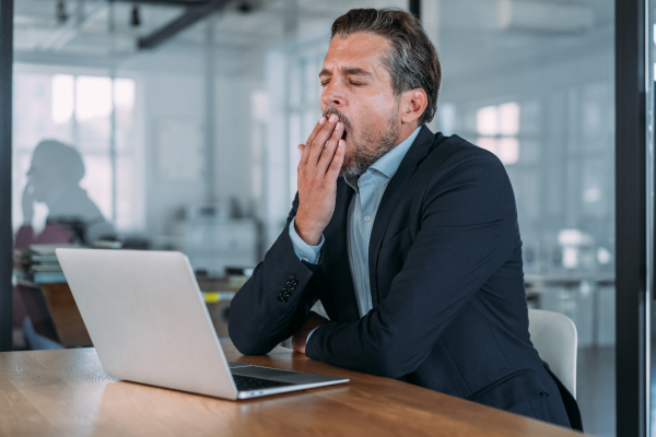 Uomo davanti al suo pc con sonnolenza diurna, tra gli effetti collaterali della melatonina