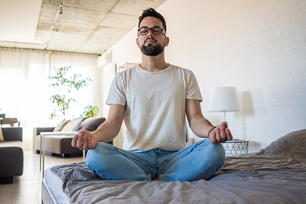 Uomo rilassato in casa, che pratica yoga e altre tecniche di rilassamento per contrastare i disturbi del sonno