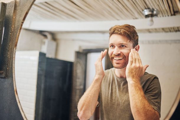 uomo-sereno-prevenendo-cisti-sebacea-adottando-routine-di-igiene-cutanea Uomo sereno nel bagno di casa, al mattino, che previene la cisti sebacea e altre problematiche della pelle adottando una routine di igiene cutanea adatta alle sue necessità