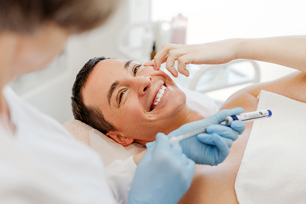 Uomo sorridente mentre segue il consiglio del medico dermatologo e non toglie da solo la sua cisti sebacea