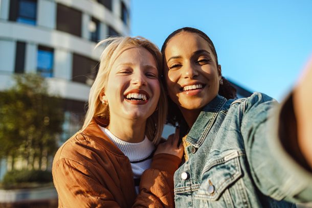 amiche-facendo-seflie-durante-passeggiata-conversando-su-progesterone-a-cosa-serve Amiche divertite che fanno un selfie durante una passeggiata in città, lungo la quale condividono informazioni su a cosa serve il progesterone e su altri temi di salute femminile