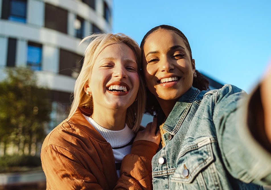 amiche-facendo-seflie-durante-passeggiata-conversando-su-progesterone-a-cosa-serve Amiche divertite che fanno un selfie durante una passeggiata in città, lungo la quale condividono informazioni su a cosa serve il progesterone e su altri temi di salute femminile