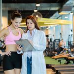 Atleta donna in palestra che conversa con la dottoressa durante la visita di medicina dello sport
