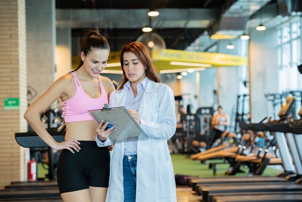 Atleta donna in palestra che conversa con la dottoressa durante la visita di medicina dello sport