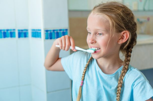 Bambina si lava i denti con dentifricio con fluoro