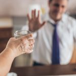 Businessman seduto alla scrivania che rifiuta il consumo combinato di alcol e psicofarmaci