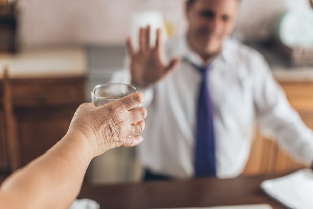 Businessman seduto alla scrivania che rifiuta il consumo combinato di alcol e psicofarmaci