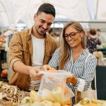 Coppia al mercato che segue una dieta per contrastare i trigliceridi alti e acquista verdure fresche