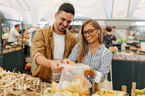Coppia al mercato che segue una dieta per contrastare i trigliceridi alti e acquista verdure fresche