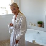 Donna in accappatoio accanto alla vasca da bagno che si occupa del suo ciclo mestruale che non sfoga