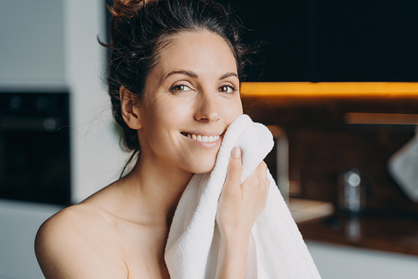 Donna che si asciuga il viso dopo il lavaggio, in quanto una corretta igiene della pelle fornisce prevenzione e cura per i casi di dermatite