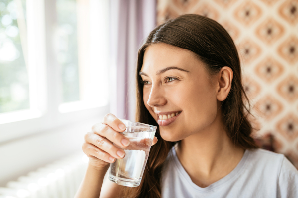 Giovane donna con bicchiere d'acqua per prendere magnesio, tra gli integratori per stress