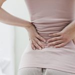 Donna che soffre di cisti di tarlov si tocca la schiena