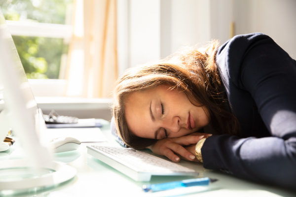 Giovane donna addormentata sulla sua scrivania, che soffre di narcolessia