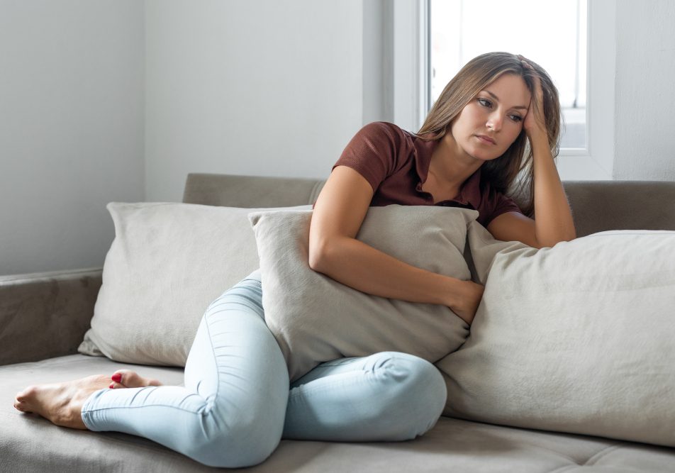 donna-che-soffre-di-nausea-da-ansia Donna seduta sul divano mostra sofferenza pe la nausea da ansia
