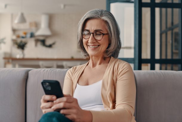 Donna matura sul suo divano guardando cellulare che soffre di cisti renali asintomatiche