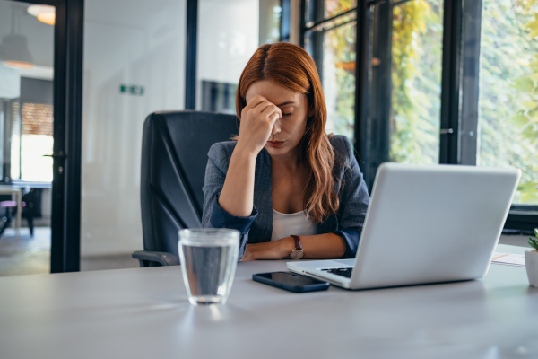 Giovane donna a lavoro, davanti al suo pc con difficoltà di concentrazione, tra gli effetti collaterali del bromazepam
