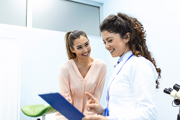 Donna sorridente che consulta la ginecologa in clinica per indagare sulla cura dello spotting durante l’ovulazione