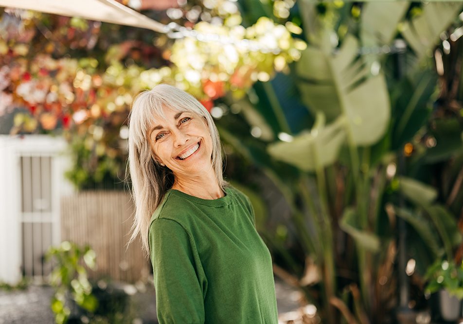 donna-in-giardino-adottando-stile-di-vita-sano-per-livelli-progesterone-menopausa Donna in menopausa sorridente nel giardino di casa che adotta uno stile di vita sano mantenendo livelli di progesterone adatti alla sua età
