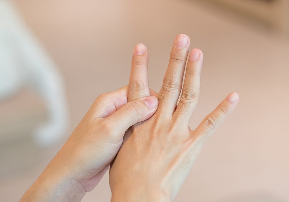 Donna che si tocca le dita della mano e soffre di cisti tendinea