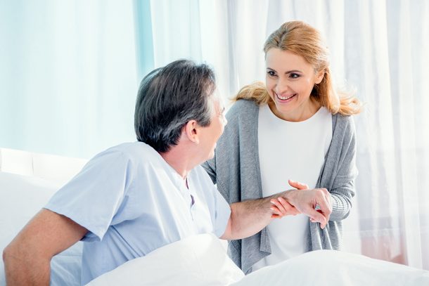 donna-visitando-marito-dopo-trapianto-midollo-osseo Donna in ospedale che fa visita al marito, aiutandolo a stare alzato nel letto in seguito al trapianto di midollo osseo