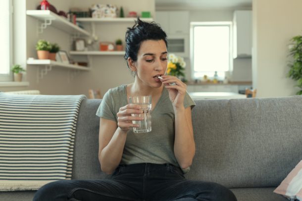 giovane-donna-che-assume-betametasone Giovane donna con bicchiere d'acqua in mano assume betametasone per malattia dermatologica