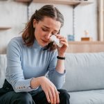 Giovane donna seduta su un divano sperimenta che piangere fa bene