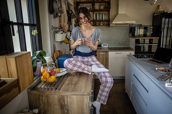 Ragazza sorridente al mattino in cucina che adotta rimedi naturali per debellare la cistite, tra cui la corretta idratazione e l’alimentazione equilibrata