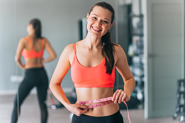 Ragazza di buon umore all’interno di una palestra che combatte contro il gonfiore addominale dato da livelli alti di progesterone