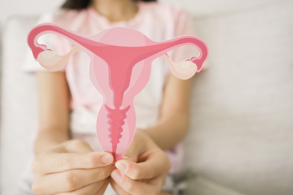 Giovane studentessa di medicina che mostra un cartoncino con la sagoma di un utero femminile per illustrare i sintomi delle cisti ovariche