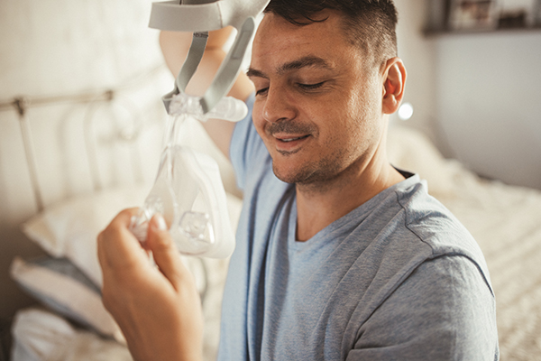 Uomo al risveglio al mattino che si toglie il macchinario CPAP per trattare l’apnea notturna