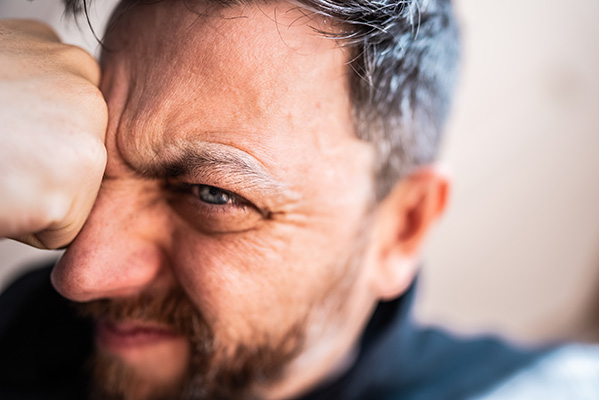 Uomo di mezza età con la fronte corrucciata e un’espressione frustrata che avverte sintomi di forte stress