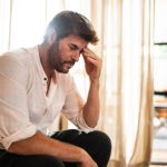 Uomo si tocca le tempie a causa di mal di testa intenso, tra i sintomi della meningoencefalite