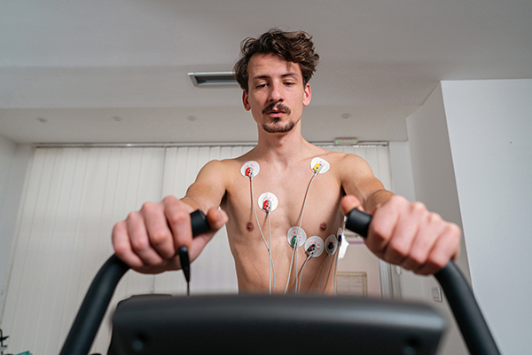 Uomo con elettrodi sul petto che effettua un test da sforzo sulla cyclette richiesto dal suo medico per l’ottenimento del certificato medico per l’iscrizione in palestra