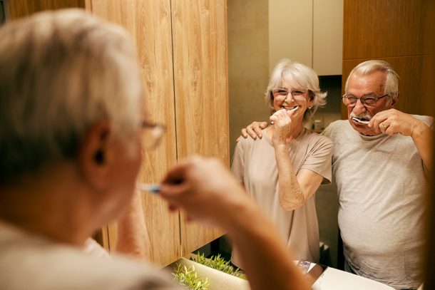 coppia-anziana-in-bagno-seguendo-indicazioni-del-dentista-su-quante-volte-lavare-i-denti Coppia anziana in bagno davanti allo specchio che segue le indicazioni del dentista su quante volte lavare i denti
