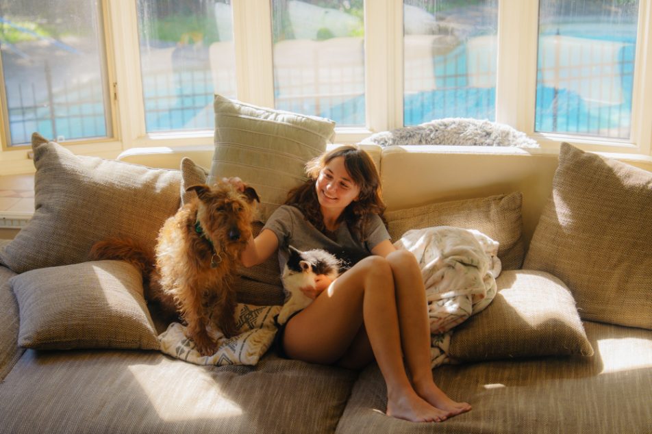 donna-che-ha-assicurazione-animali-domestici Giovane donna con cane e gatto sul divano che ha stipulato un'assicurazione per animali domestici
