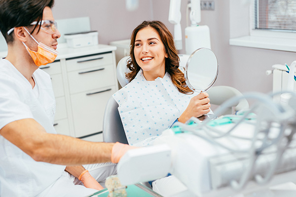 Donna dal dentista sorridente con specchio in mano